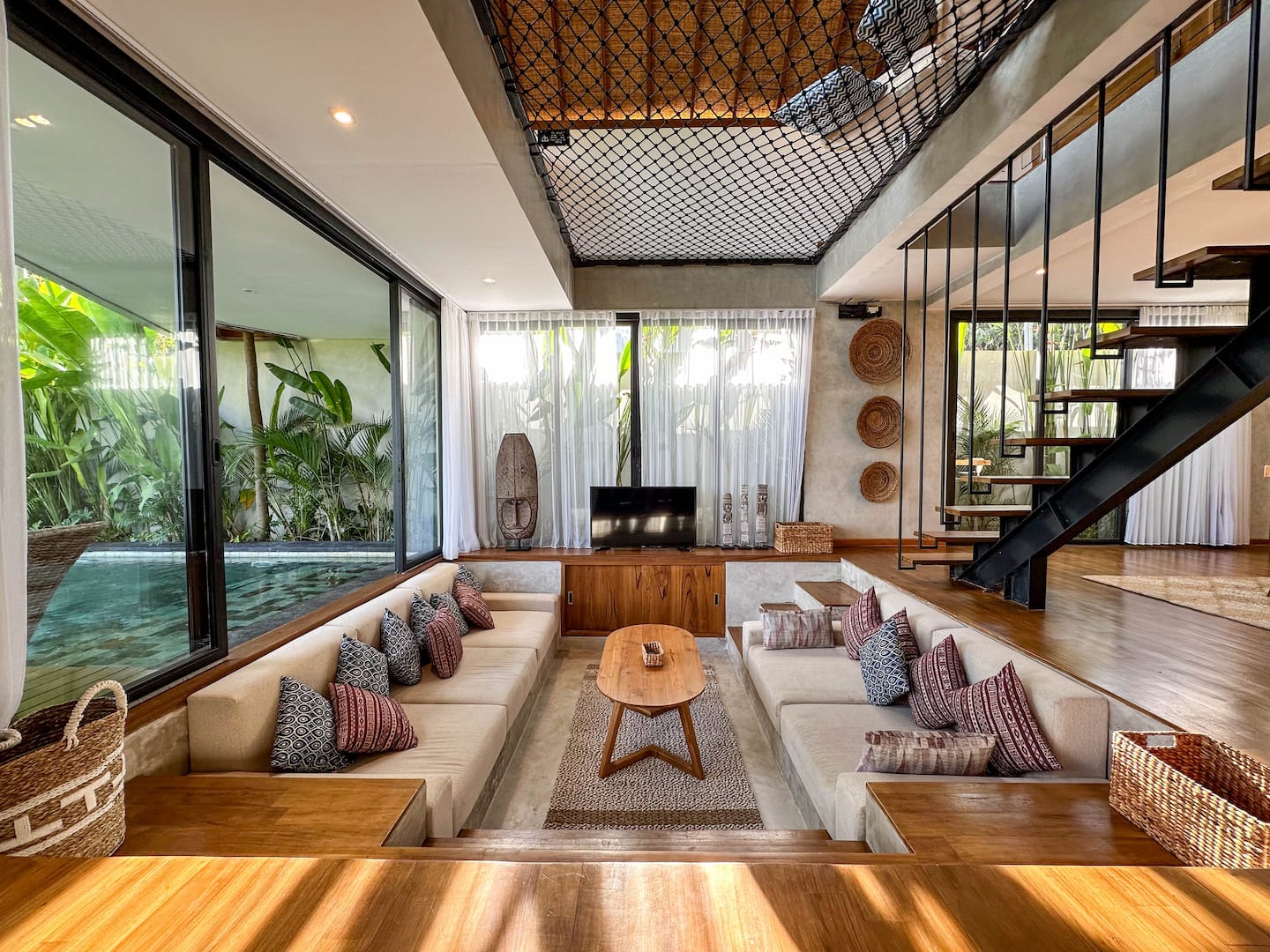 Sunken lounge with cream cushions facing the pool and rice fields