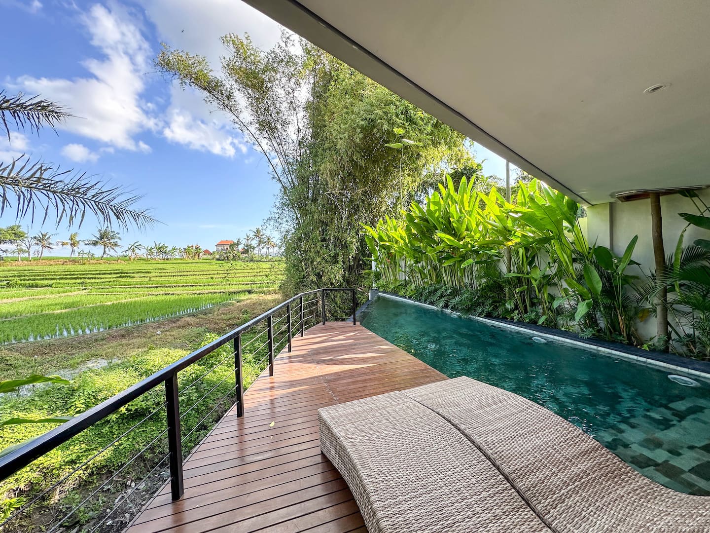 Private pool running along the edge of green rice paddies